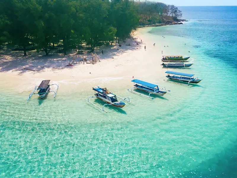 Bali: outrigger canoes moored along a white sand beach, on turquoise water